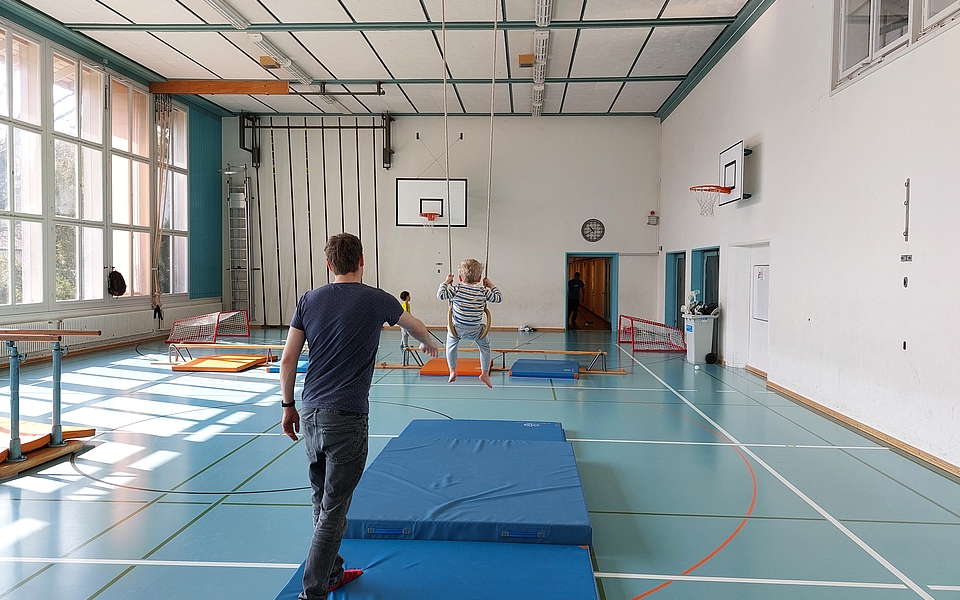 Kinder probieren mit ihren Eltern tolle Kunststücke in der Turnhalle.